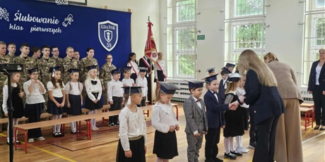 Powiększ grafikę: Uczniowie w sali gimnastycznej otrzymują legitymacje.