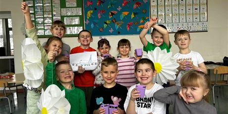 Powiększ grafikę: Uczniowie prezentują kwiaty i wykonane prace w sali lekcyjnej.