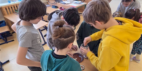 Powiększ grafikę: Uczniowie wysiewają rzeżuchę w nakrętkach słoików w sali lekcyjnej.