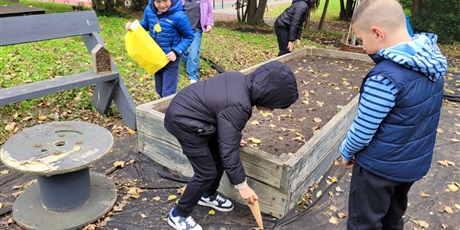 Powiększ grafikę: Uczniowie w ogródku szkolnym, wykonują zadania.