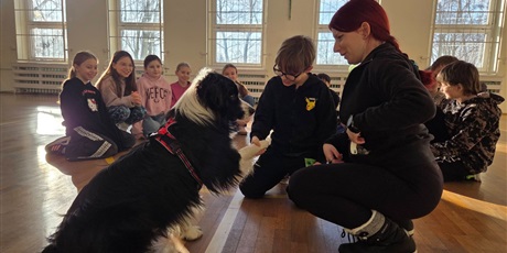Powiększ grafikę: Uczniowie podczas zajęć z psim terapeutą w sali gimnastycznej.