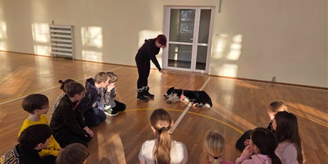 Powiększ grafikę: Uczniowie podczas zajęć z psim terapeutą w sali gimnastycznej.