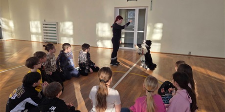 Powiększ grafikę: Uczniowie podczas zajęć z psim terapeutą w sali gimnastycznej.