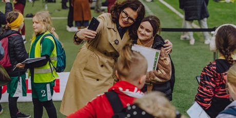 Powiększ grafikę: Pani prezydent Gdańska pozuje do selfi z uczennicą na stadionie piłkarskim.