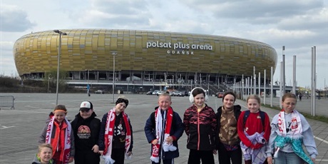 Powiększ grafikę: Uczniowie w szalikach w barwach narodowych przed stadionem.