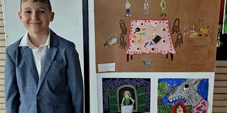 Powiększ grafikę: Uczeń na tle plastycznych prac konkursowych.