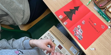 Powiększ grafikę: Uczniowie w sali lekcyjnej wykonują kartki świąteczne.