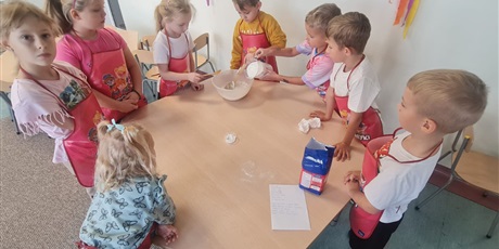 Powiększ grafikę: Uczniowie w sali lekcyjnej przygotowują ciasto na bułki