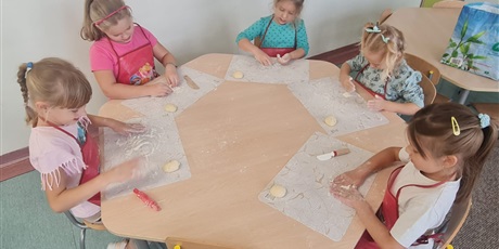 Powiększ grafikę: Uczniowie w sali lekcyjnej przygotowują  bułki.