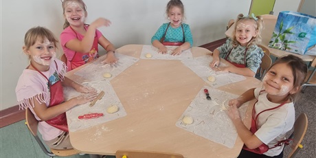 Powiększ grafikę: Uczniowie w sali lekcyjnej przygotowują  bułki.