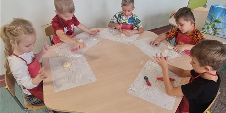 Powiększ grafikę: Uczniowie w sali lekcyjnej przygotowują  bułki.