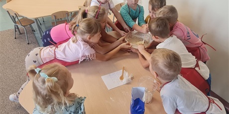 Powiększ grafikę: Uczniowie w sali lekcyjnej przygotowują ciasto na bułki.