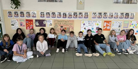 Powiększ grafikę: Zbiorowe zdjęcie uczniów pod napisem "Dzień Tabliczki Mnożenia" na korytarzu szkolnym.