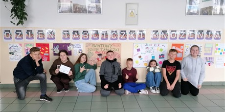 Powiększ grafikę: Zbiorowe zdjęcie uczniów pod napisem "Dzień Tabliczki Mnożenia" na korytarzu szkolnym.