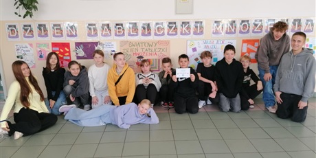 Powiększ grafikę: Zbiorowe zdjęcie uczniów pod napisem "Dzień Tabliczki Mnożenia" na korytarzu szkolnym.