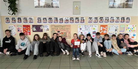 Powiększ grafikę: Zbiorowe zdjęcie uczniów pod napisem "Dzień Tabliczki Mnożenia" na korytarzu szkolnym.