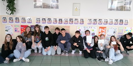 Powiększ grafikę: Zbiorowe zdjęcie uczniów pod napisem "Dzień Tabliczki Mnożenia" na korytarzu szkolnym.