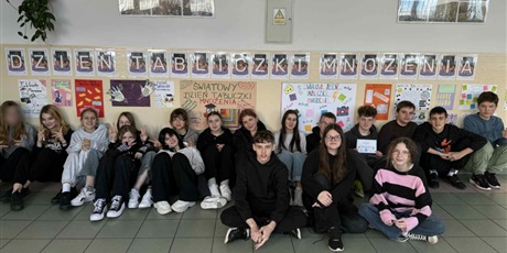 Powiększ grafikę: Zbiorowe zdjęcie uczniów pod napisem "Dzień Tabliczki Mnożenia" na korytarzu szkolnym.