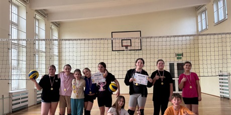 Powiększ grafikę: Zbiorowe zdjęcie uczniów z medalami i dyplomami w sali gimnastycznej.