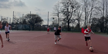 Powiększ grafikę: Uczniowie podczas gry w piłkę nożną na boisku szkolnym.