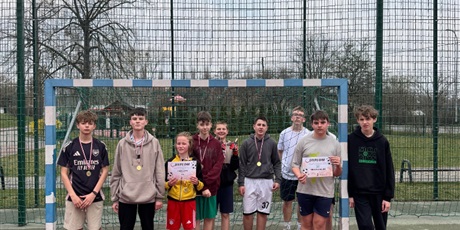 Powiększ grafikę: Uczniowie z medalami i dyplomami w bramce na boisku szkolnym.