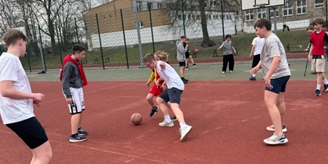 Powiększ grafikę: Uczniowie podczas gry w piłkę nożną na boisku szkolnym.