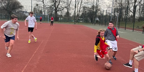 Powiększ grafikę: Uczniowie podczas gry w piłkę nożną na boisku szkolnym.