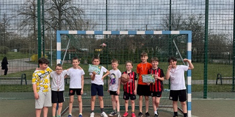 Powiększ grafikę: Uczniowie z medalami i dyplomami w bramce na boisku szkolnym.