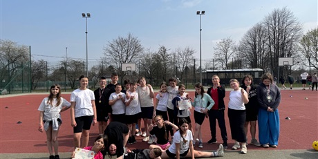 Powiększ grafikę: Uczniowie z medalami i dyplomem na boisku szkolnym.