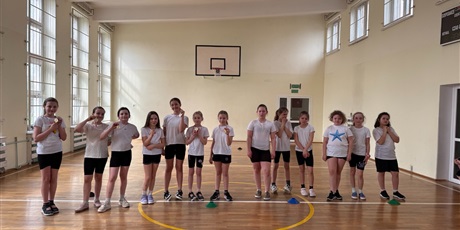 Powiększ grafikę: Zbiorowe zdjęcie uczennic z medalami w sali gimnastycznej.