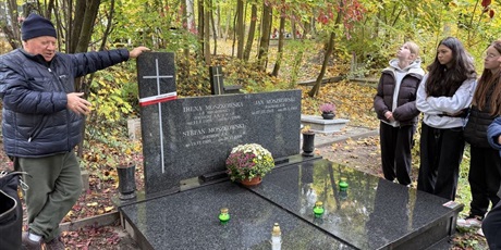 Powiększ grafikę: Uczniowie i starszy mężczyzna  przy grobie.