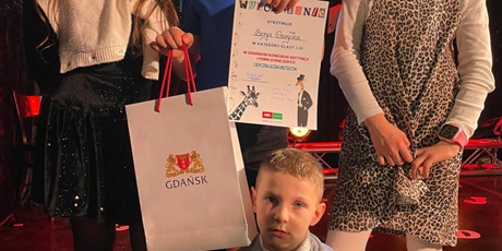 Powiększ grafikę: Uczniowie z dyplomem i nagrodą.