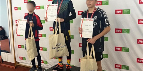 Powiększ grafikę: Uczniowie na podium z medalami i nagrodami.