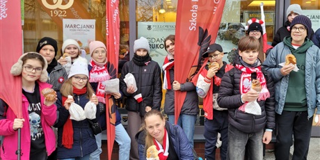 Powiększ grafikę: Uczniowie i nauczyciele przy piekarni z rogalami.