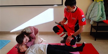 Powiększ grafikę: Uczniowie i ratownik medyczny podczas zajęć z pierwszej pomocy.