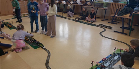 Powiększ grafikę: Uczniowie sterują pociągami z klocków poruszającymi się po zbudowanych torach kolejowych.