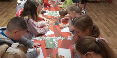 Powiększ grafikę: Uczniowie przy stole podczas wykonywania prac plastycznych.