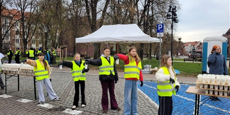 Powiększ grafikę: Wolontariusze podczas podawania napojów na trasie maratonu.
