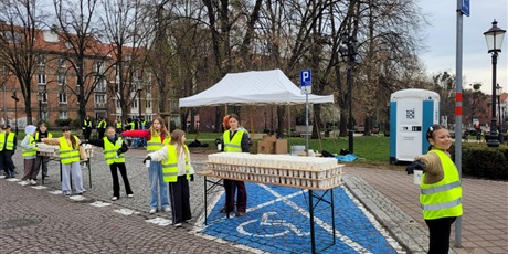 Powiększ grafikę: Wolontariusze podczas podawania napojów na trasie maratonu.