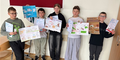 Powiększ grafikę: Uczniowie prezentujący swoje prace konkursowe na korytarzu szkolnym..