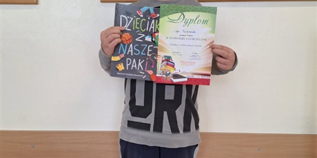 Powiększ grafikę: Uczeń z dyplomem i książką  za udział w konkursie