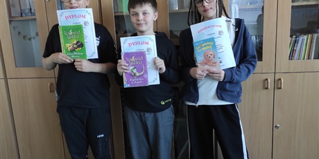 Powiększ grafikę: Uczniowie z dyplomami i nagrodami za konkurs czytelniczy w sali lekcyjnej.
