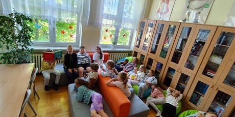 Powiększ grafikę: Uczniowie w czytelni słuchają czytanej przez kolegę książki.