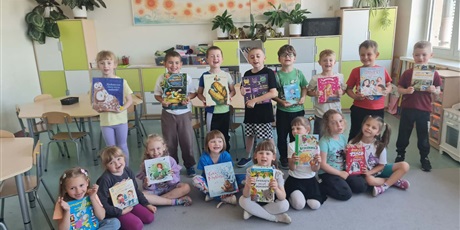 Powiększ grafikę: Zbiorowe zdjęcie uczniów prezentujących książki w sali lekcyjnej.