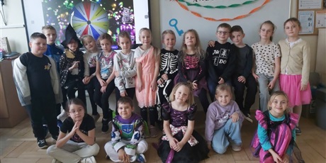 Powiększ grafikę: Zbiorowe zdjęcie uczniów w przebraniach andrzejkowych w sali lekcyjnej.