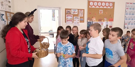 Powiększ grafikę: Uczniowie w sali lekcyjnej losują wróżby andrzejkowe.