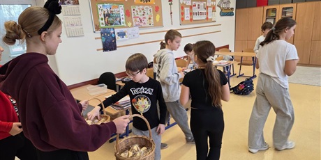 Powiększ grafikę: Uczniowie w sali lekcyjnej losują wróżby andrzejkowe.