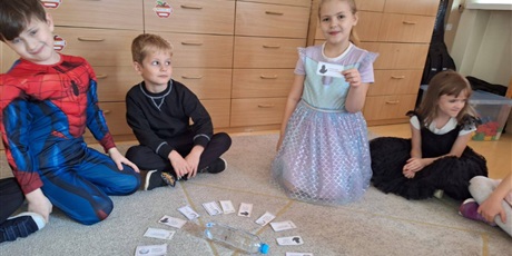 Powiększ grafikę: Uczniowie w sali lekcyjnej losują wróżby andrzejkowe.