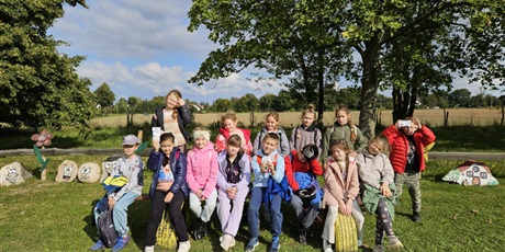 Powiększ grafikę: Zbiorowe zdjęcie uczniów w zagrodzie wiejskiej.