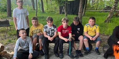 Powiększ grafikę: Chłopcy siedzący na ławce przy ognisku